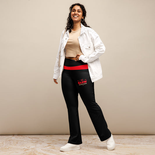 A woman is standing, wearing black flare leggings with a red waistband and 'GLOW Golden Hours' text on the front. She has her hands on her hips, smiling at the camera.